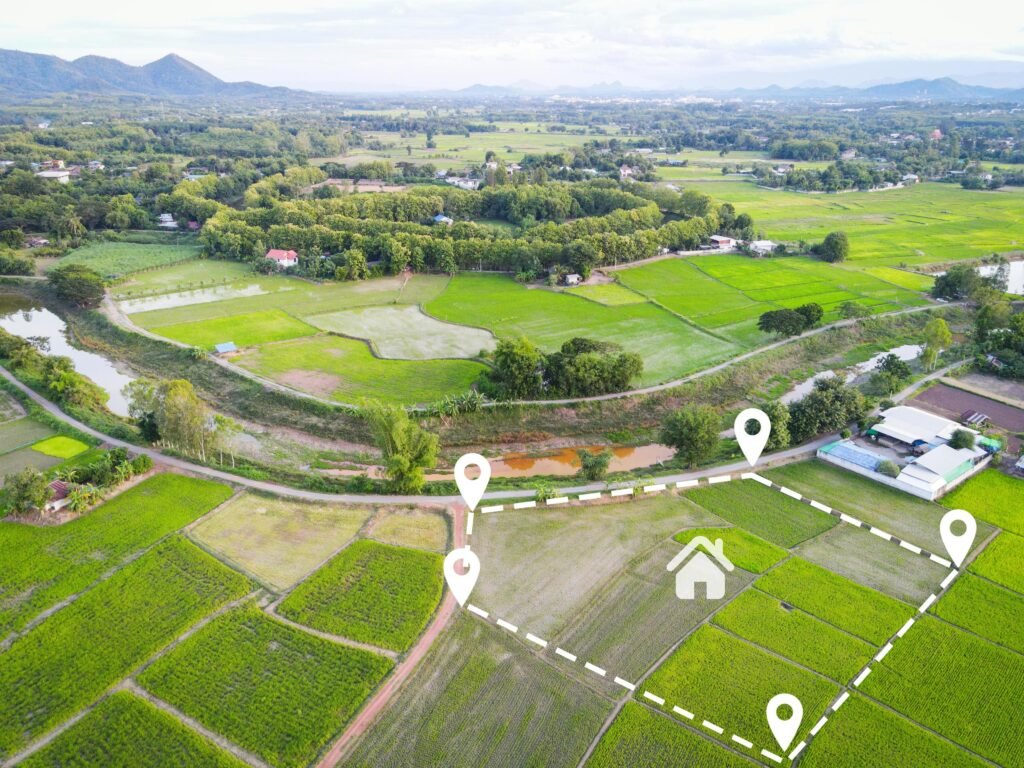 Aerial view of a vacant residential plot of land with clear boundaries, green surroundings, and an access road.